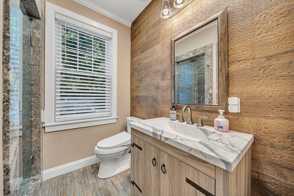 125 Union Street Natick, MA 01760 - Photo 15 of 38 a bathroom with a granite countertop toilet a sink a mirror and a window