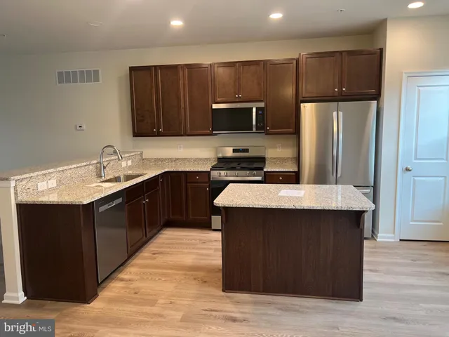 a kitchen with kitchen island a sink wooden cabinets and stainless steel appliances