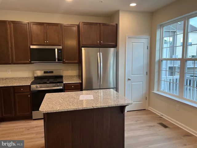 a kitchen with granite countertop a refrigerator and a stove top oven