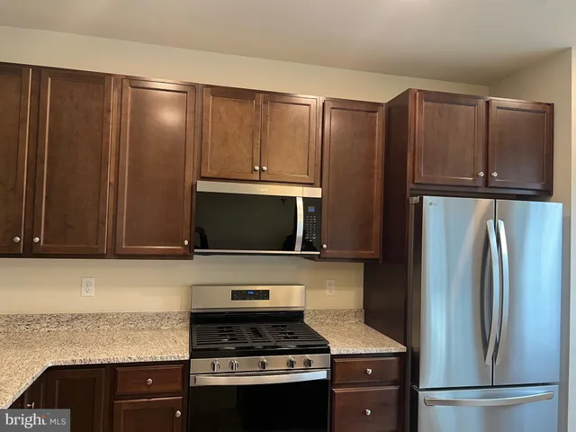 a kitchen with granite countertop a refrigerator stove and microwave