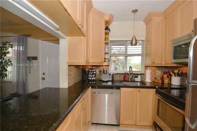 a kitchen with stainless steel appliances granite countertop a sink a stove and refrigerator