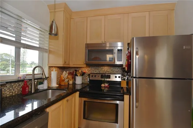 a kitchen with granite countertop a refrigerator stove and sink