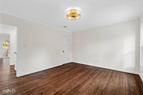 a view of an empty room with wooden floor and window
