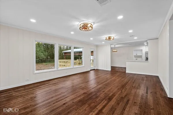 a view of an empty room with window and wooden floor