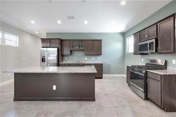 a kitchen with stainless steel appliances granite countertop a stove a sink and a microwave