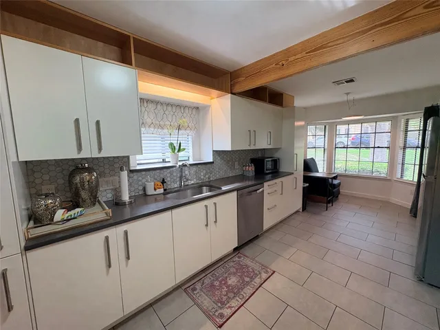 a large kitchen with granite countertop a stove a sink a window and stainless steel appliances