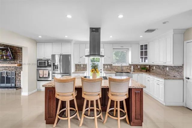 a kitchen with stainless steel appliances kitchen island granite countertop a refrigerator and a stove top oven
