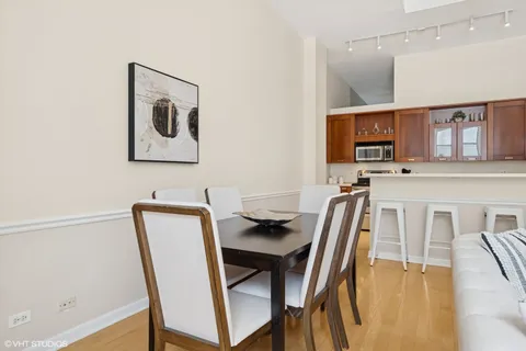 a kitchen with stainless steel appliances granite countertop a stove top oven a sink a dining table and chairs