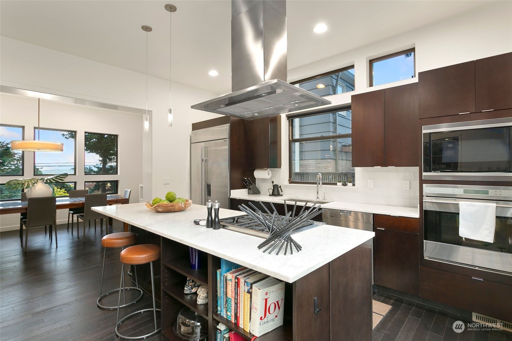 2717 36th Avenue Southwest Seattle, WA 98126 - Photo 9 of 40 a kitchen with stainless steel appliances a sink a stove top oven a dining table and chairs with wooden floor
