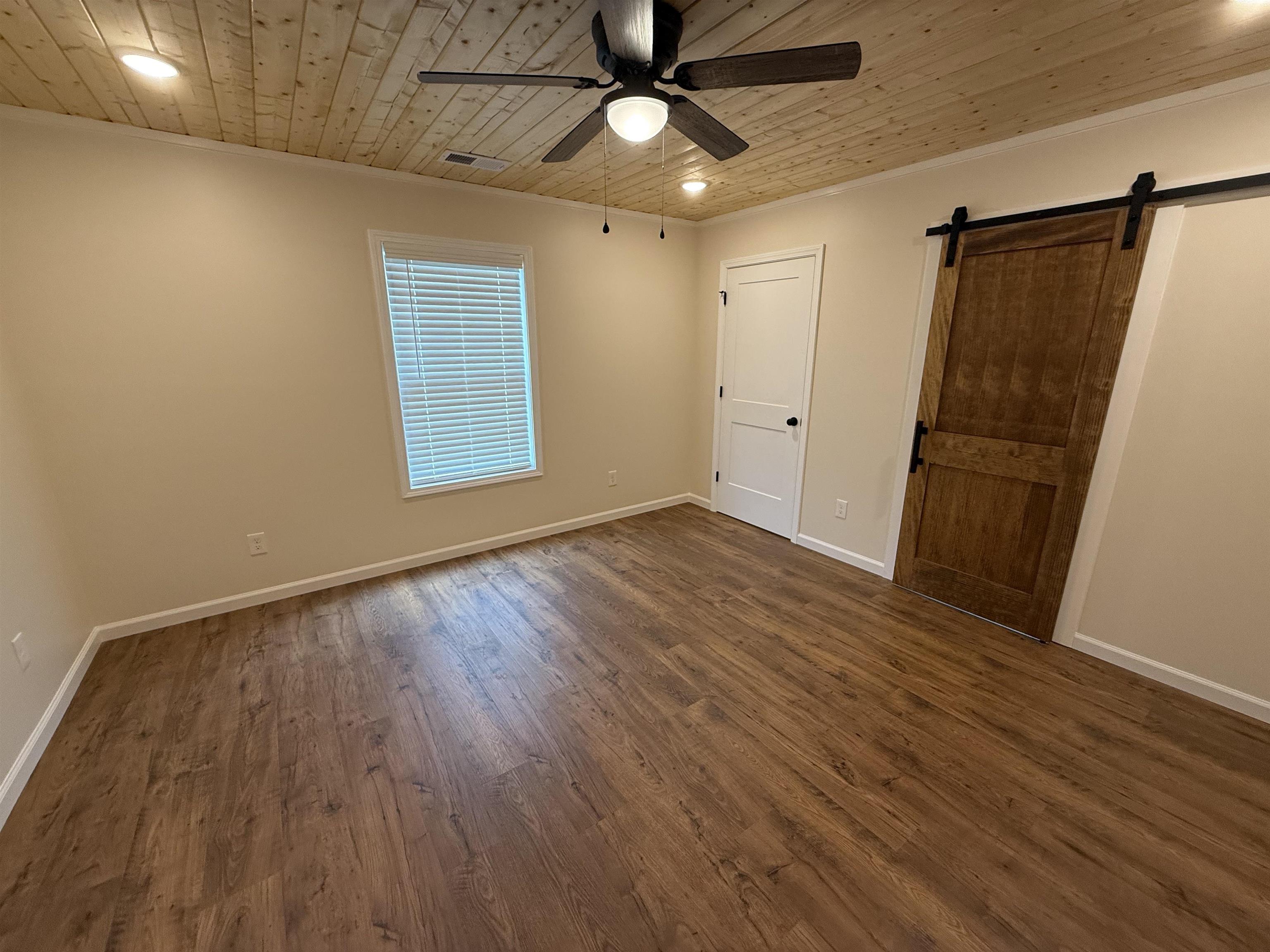 104 Young Drive Selmer, TN 38375 - Photo 9 of 12 a view of an empty room with wooden floor and a ceiling fan