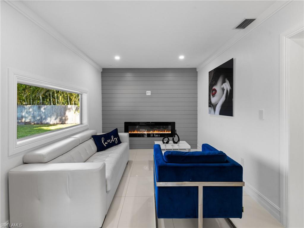 1837 51st Terrace Southwest Naples, FL 34116 - Photo 15 of 35 Bar area featuring: picture window, wine fridge, high gloss cabinets, quartz countertop, crown molding, shiplap accent wall, recessed lighting, and a electric heated fireplace.