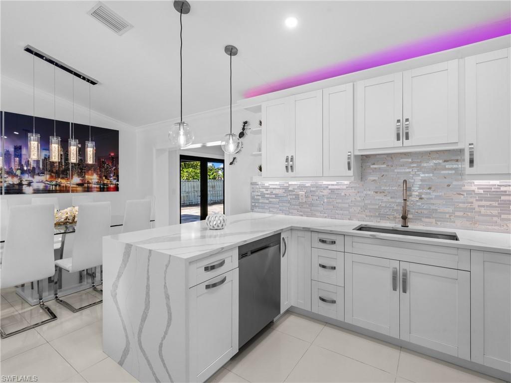 1837 51st Terrace Southwest Naples, FL 34116 - Photo 8 of 35 Kitchen with a peninsula, backsplash, open shelves, decorative light fixtures and vaulted ceiling