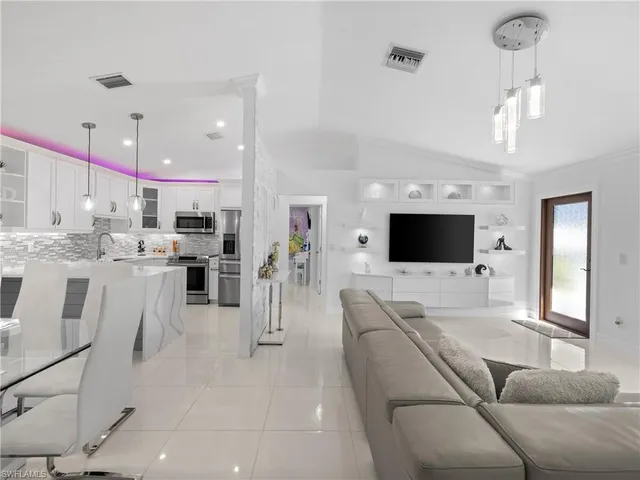 a living room with furniture a flat screen tv and kitchen view