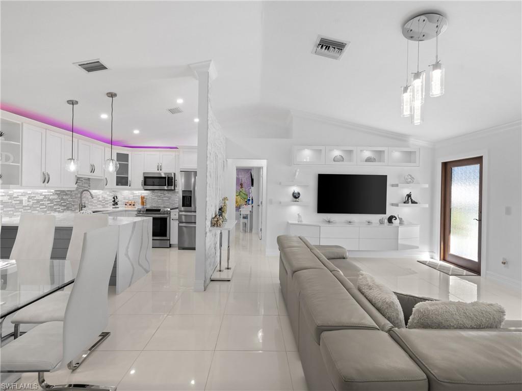 1837 51st Terrace Southwest Naples, FL 34116 - Photo 9 of 35 Living room with light tile patterned floors, vaulted ceiling, crown molding and recessed lighting