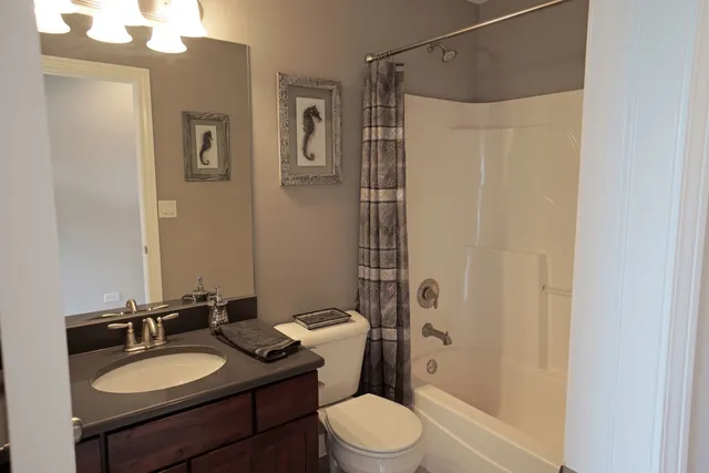 a bathroom with a granite countertop sink toilet a mirror a vanity and shower