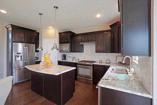 a kitchen with stainless steel appliances granite countertop a sink stove and refrigerator