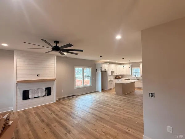 a view of empty room with kitchen and fireplace