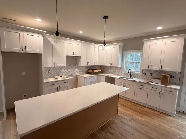 a large white kitchen with lots of counter space a sink appliances and cabinets