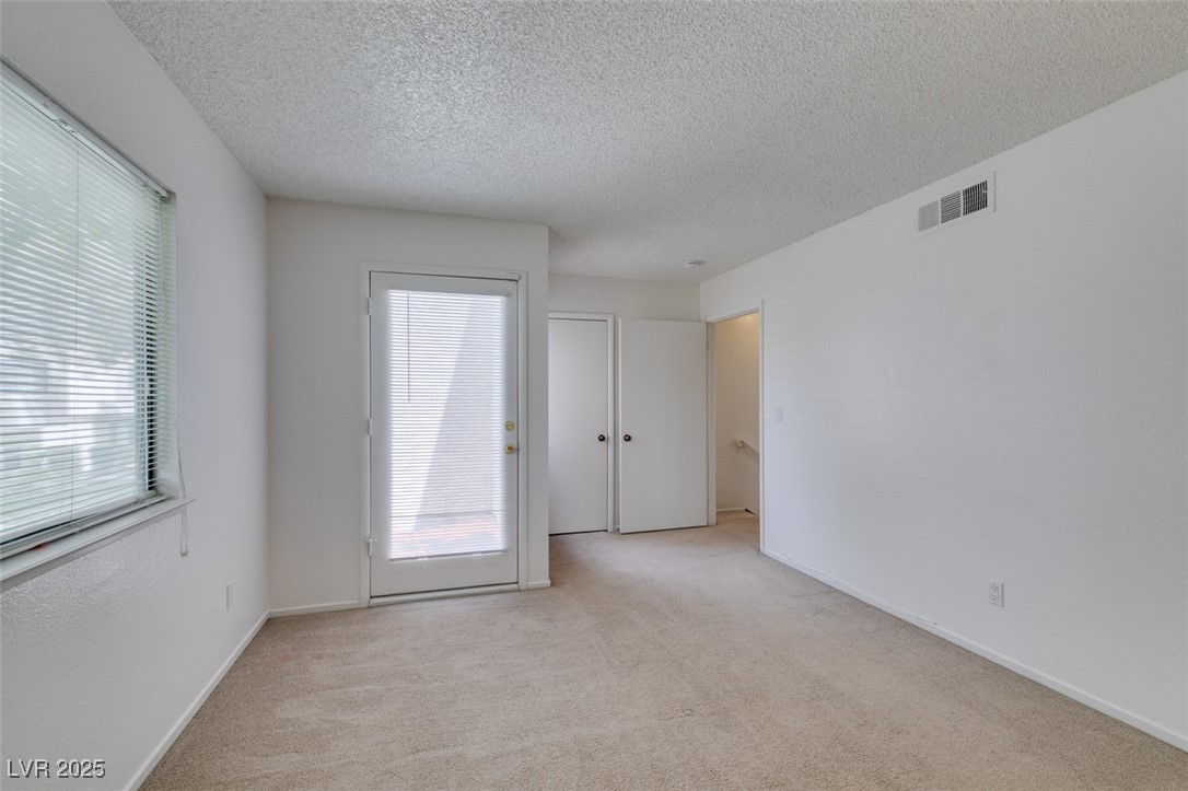 2681 Ruthe Duarte Avenue Las Vegas, NV 89121 - Photo 31 of 43 Spare room featuring visible vents, plenty of natural light, light colored carpet, and a textured ceiling