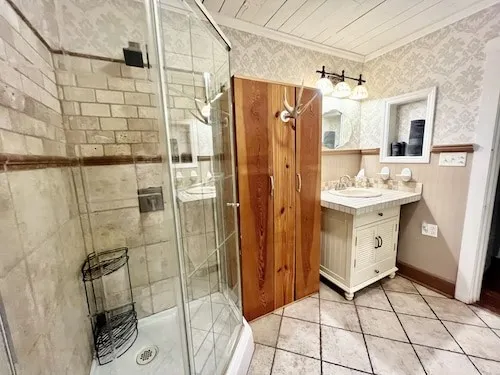 a spacious bathroom with a double vanity sink a mirror and shower