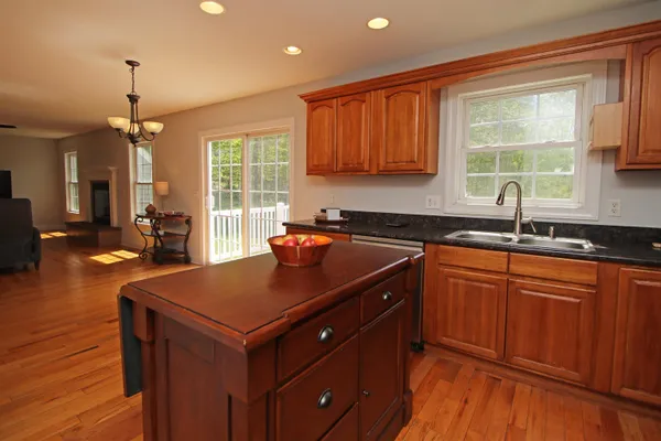 a kitchen with stainless steel appliances granite countertop a sink a stove and a wooden floors