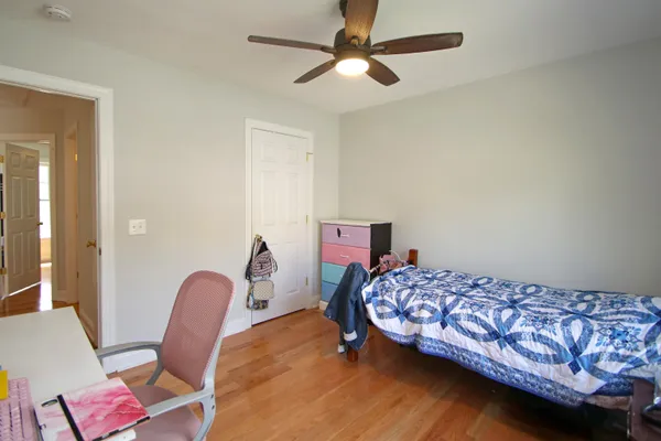 a bedroom with a bed a chair and wooden floor