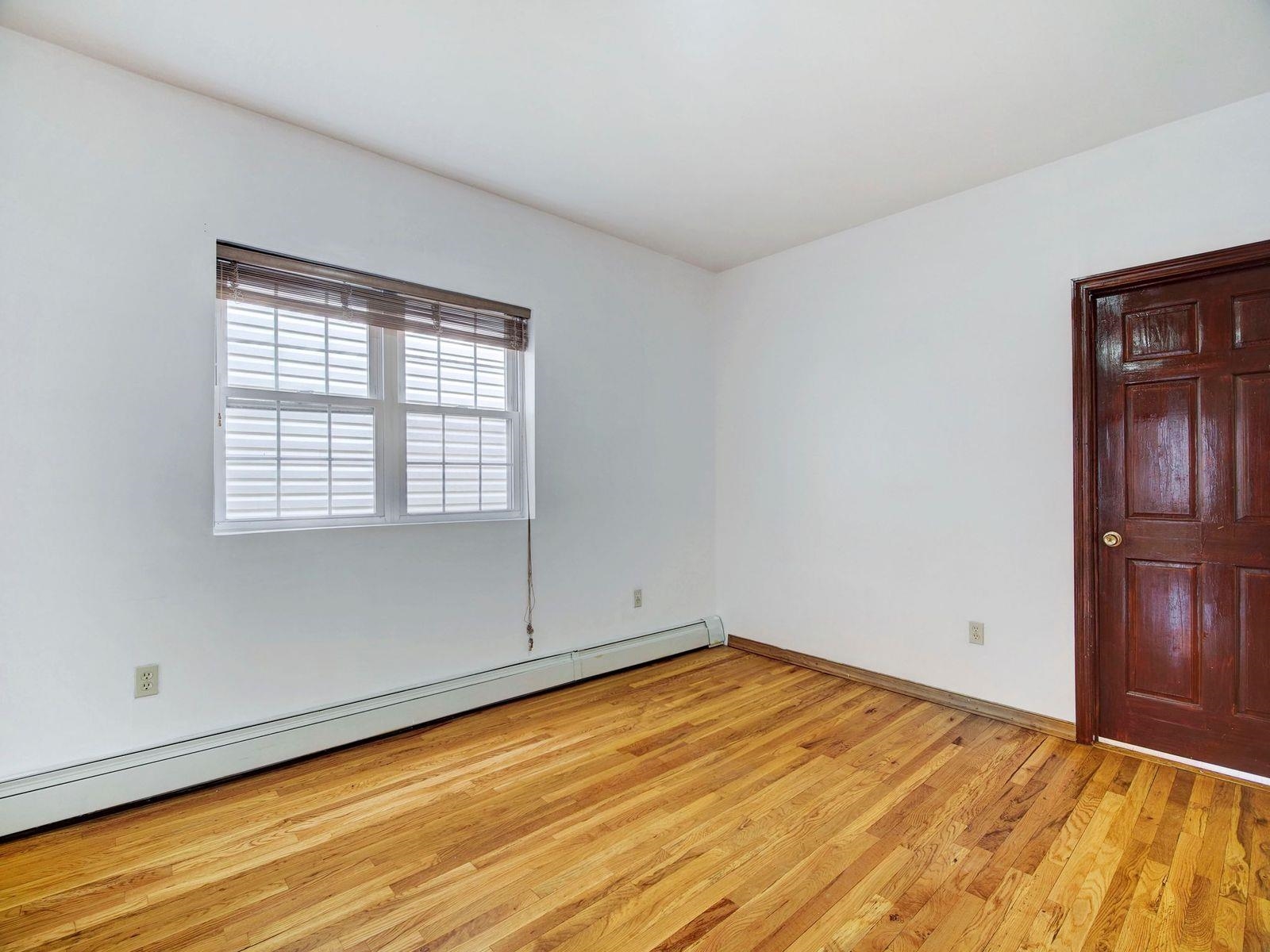 921 Paterson Plank Road, Unit 2 North Bergen, NJ 07047 - Photo 6 of 15 an empty room with wooden floor and windows