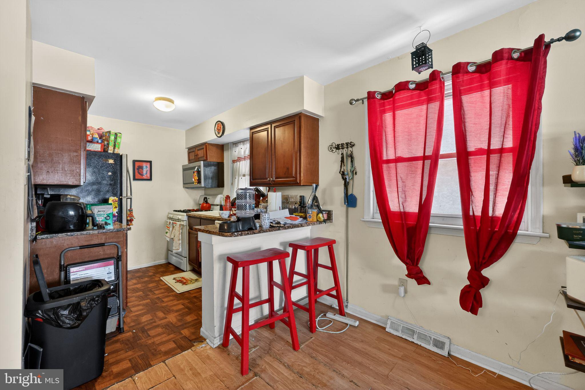 2406 Township Line Road Havertown, PA 19083 - Photo 9 of 15 a kitchen with stainless steel appliances kitchen island granite countertop a refrigerator a stove top oven a dining table and chairs with wooden floor