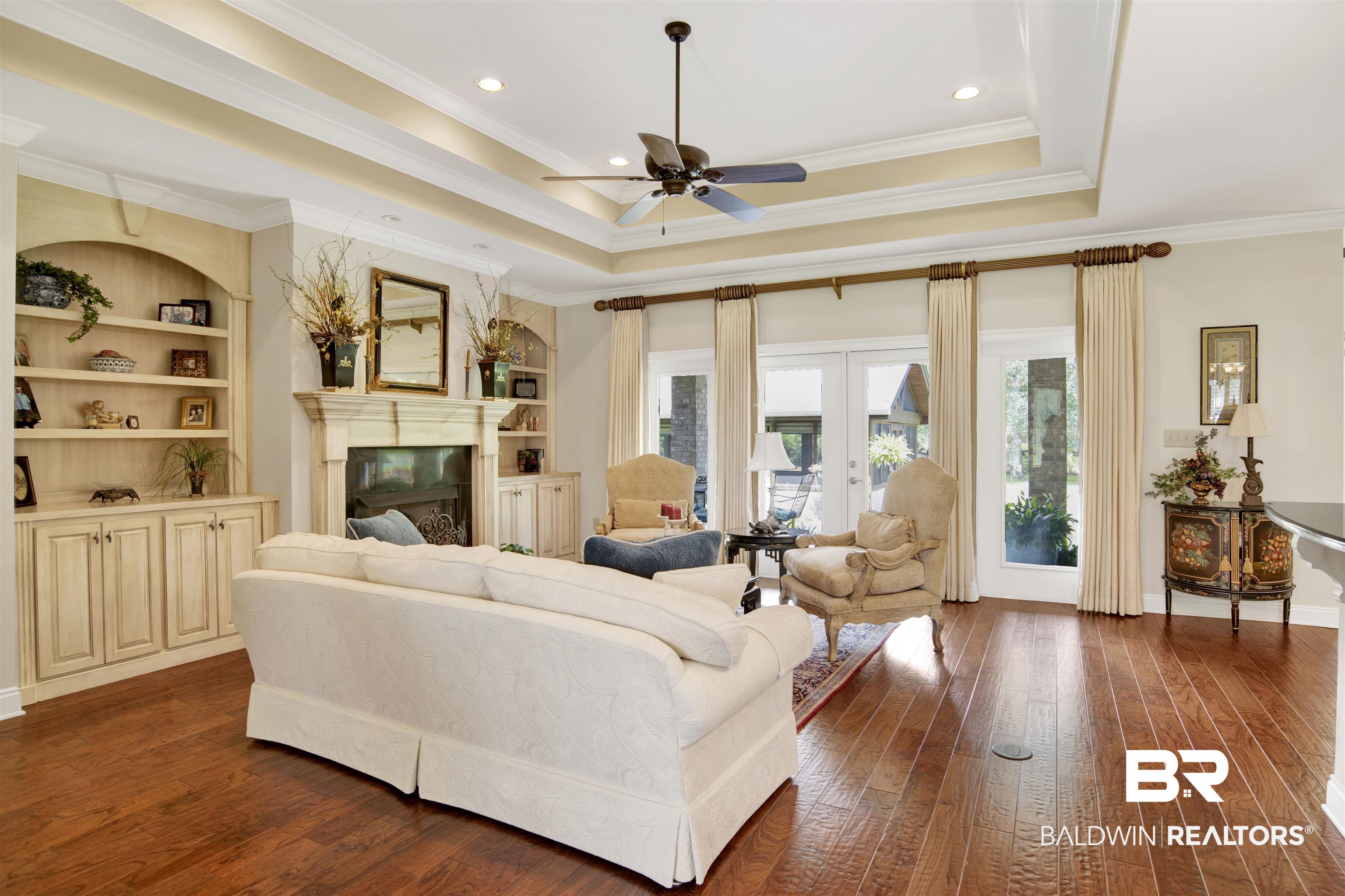 8358 Forest Lane Foley, AL 36535 - Photo 38 of 46 Living area featuring ceiling fan, a glass covered fireplace, dark wood finished floors, crown molding, and a raised ceiling