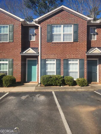 a front view of a house with yard and parking