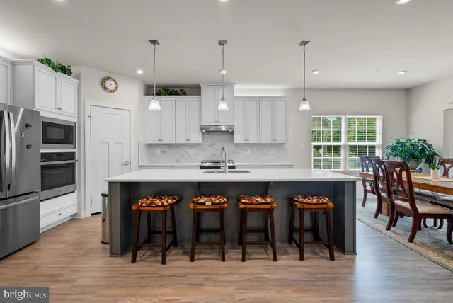 a large kitchen with stainless steel appliances a large center island and a wooden floor