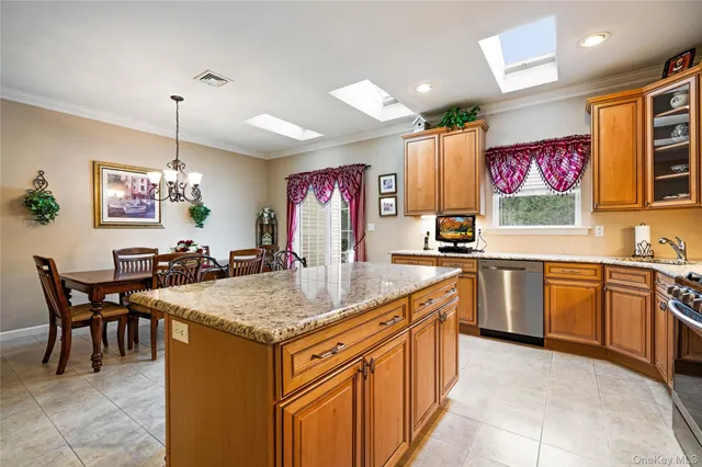 a kitchen with stainless steel appliances granite countertop a sink dishwasher a stove a dining table chairs with kitchen island