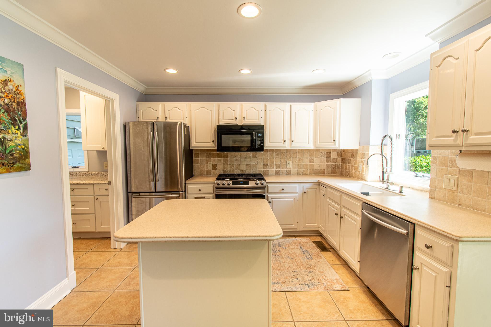 102 Jacks Point Road Oxford, MD 21654 - Photo 16 of 83 a kitchen with a sink a counter top space cabinets stainless steel appliances and a window