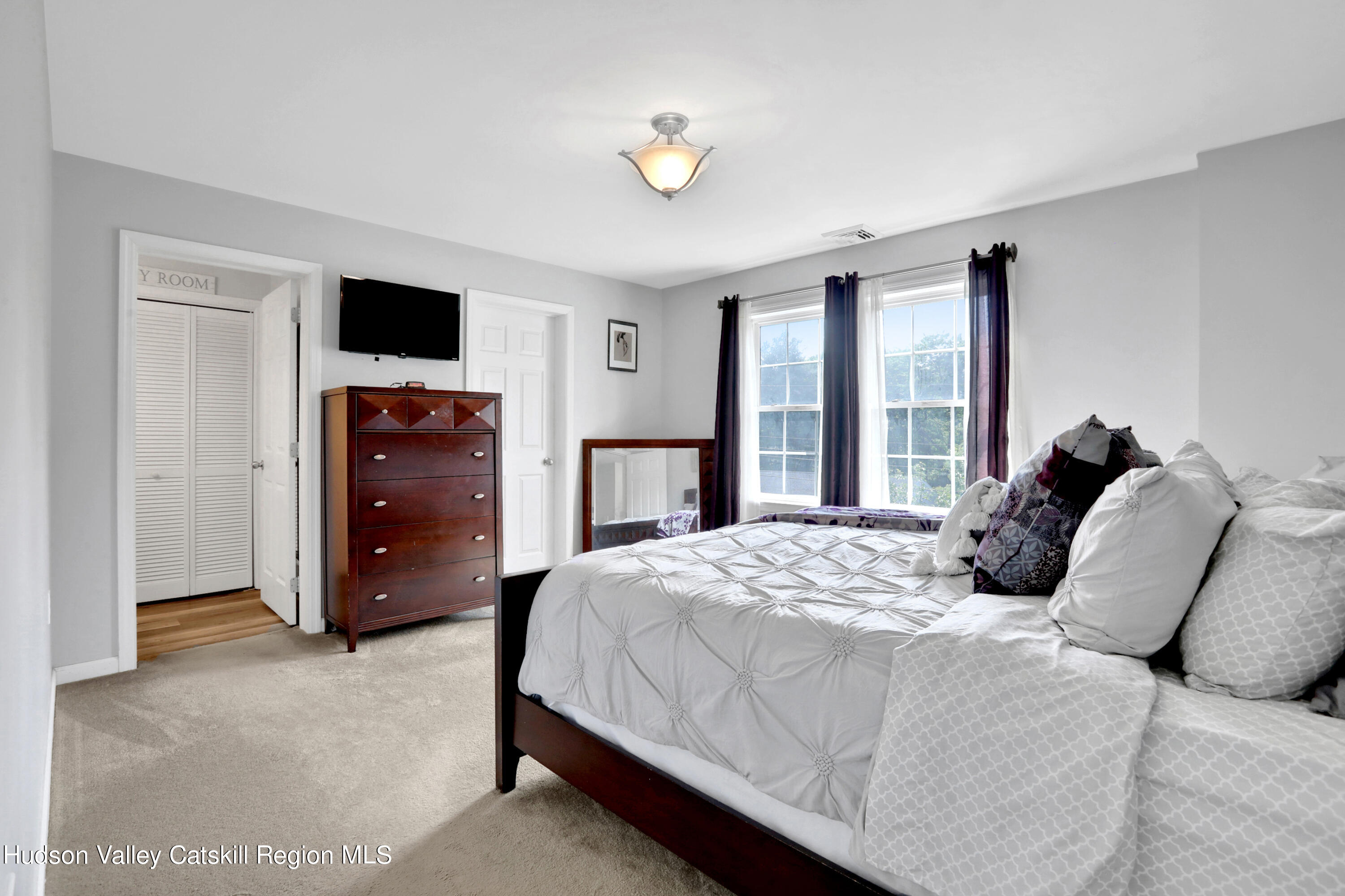 187 Russell Road Hurley, NY 12443 - Photo 18 of 33 a bedroom with a bed and a flat tv screen on dresser