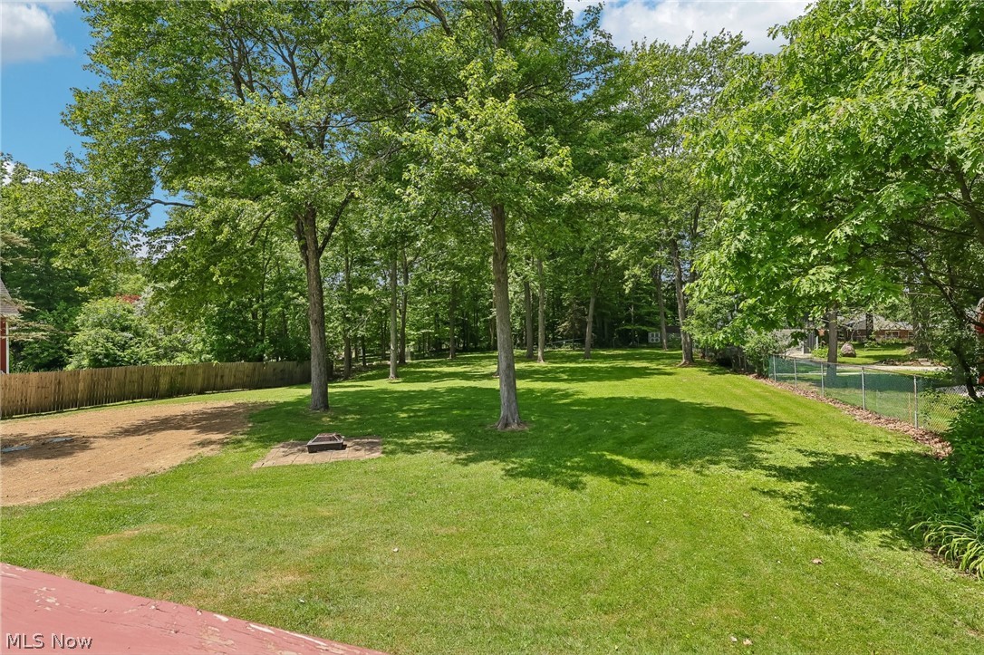 1638 South Cleveland Massillon Road Akron, OH 44321 - Photo 33 of 37 Expansive grassy lawn surrounded by mature trees, featuring a wood privacy fence along one border and a chain-link fence along another