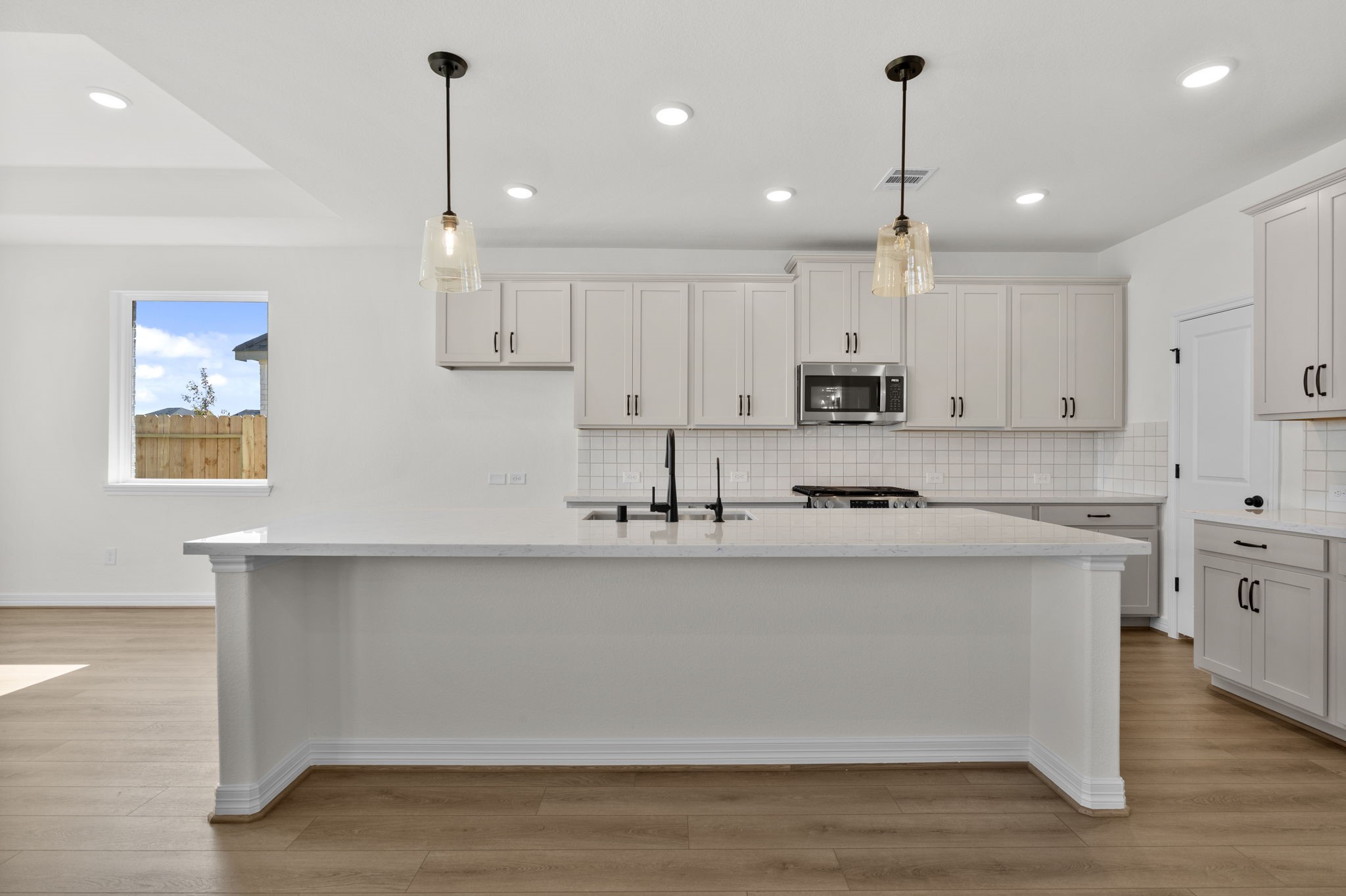 32414 Poplar Grove Lane Conroe, TX 77385 - Photo 9 of 30 This light and bright kitchen features a large quartz island, custom stained cabinets, a large sink overlooking your family room, recessed lighting, and beautiful backsplash.