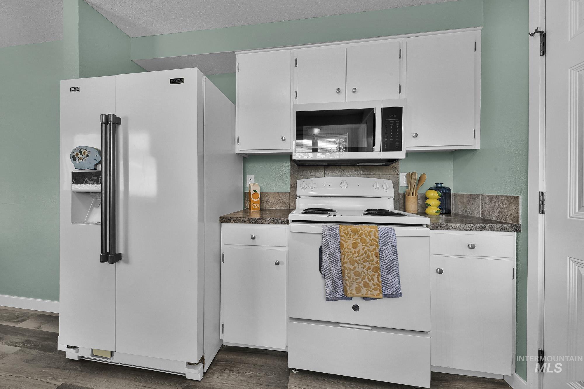 5755 Chuckwagon Road Nampa, ID 83686 - Photo 18 of 50 Kitchen featuring wood-finish flooring, white cabinetry, a built-in microwave, and a side-by-side refrigerator