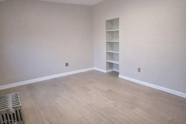 a view of an empty room with wooden floor and closet