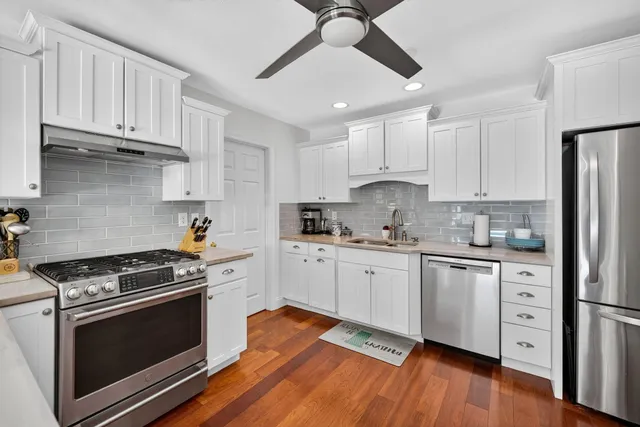 a large kitchen with cabinets wooden floor stainless steel appliances and a dining table