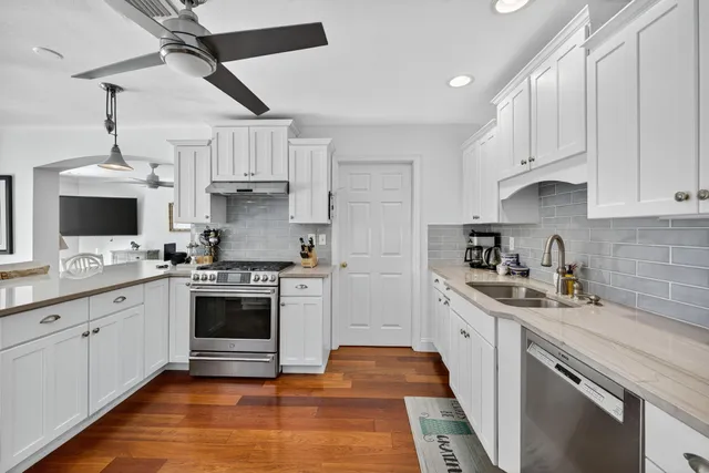 a large white kitchen with granite countertop a large window and white appliances