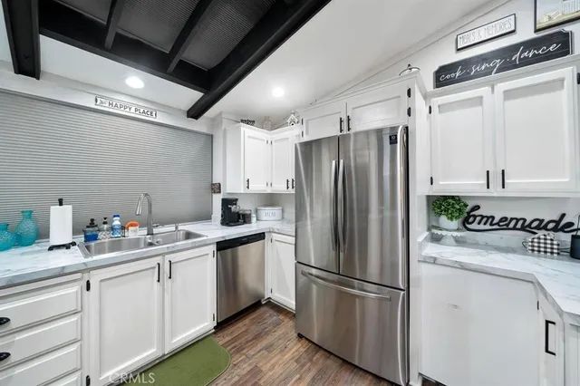a kitchen with a refrigerator a sink dishwasher and white cabinets with wooden floor
