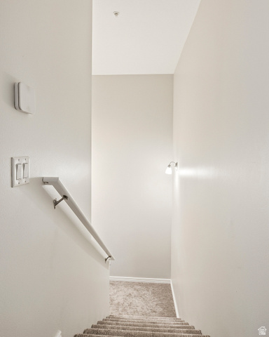 1177 Northfield Road, Unit 26 Cedar City, UT 84721 - Photo 19 of 45 Carpeted staircase with a white handrail, illuminated by a wall-mounted sconce