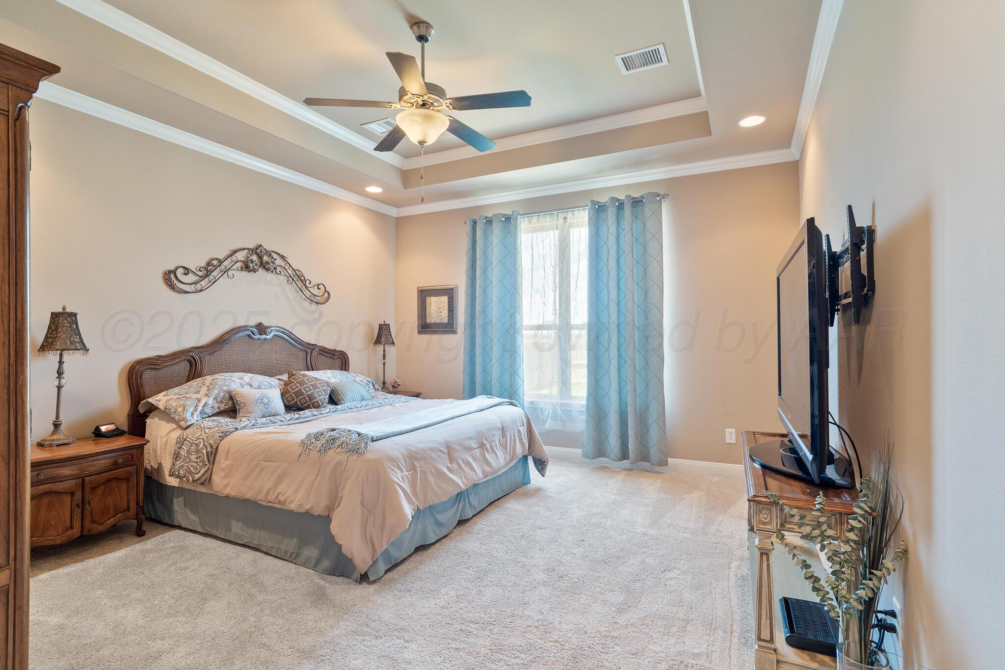 7116 Sinclair Street Amarillo, TX 79119 - Photo 12 of 23 a bedroom with a bed flat screen tv and a chandelier