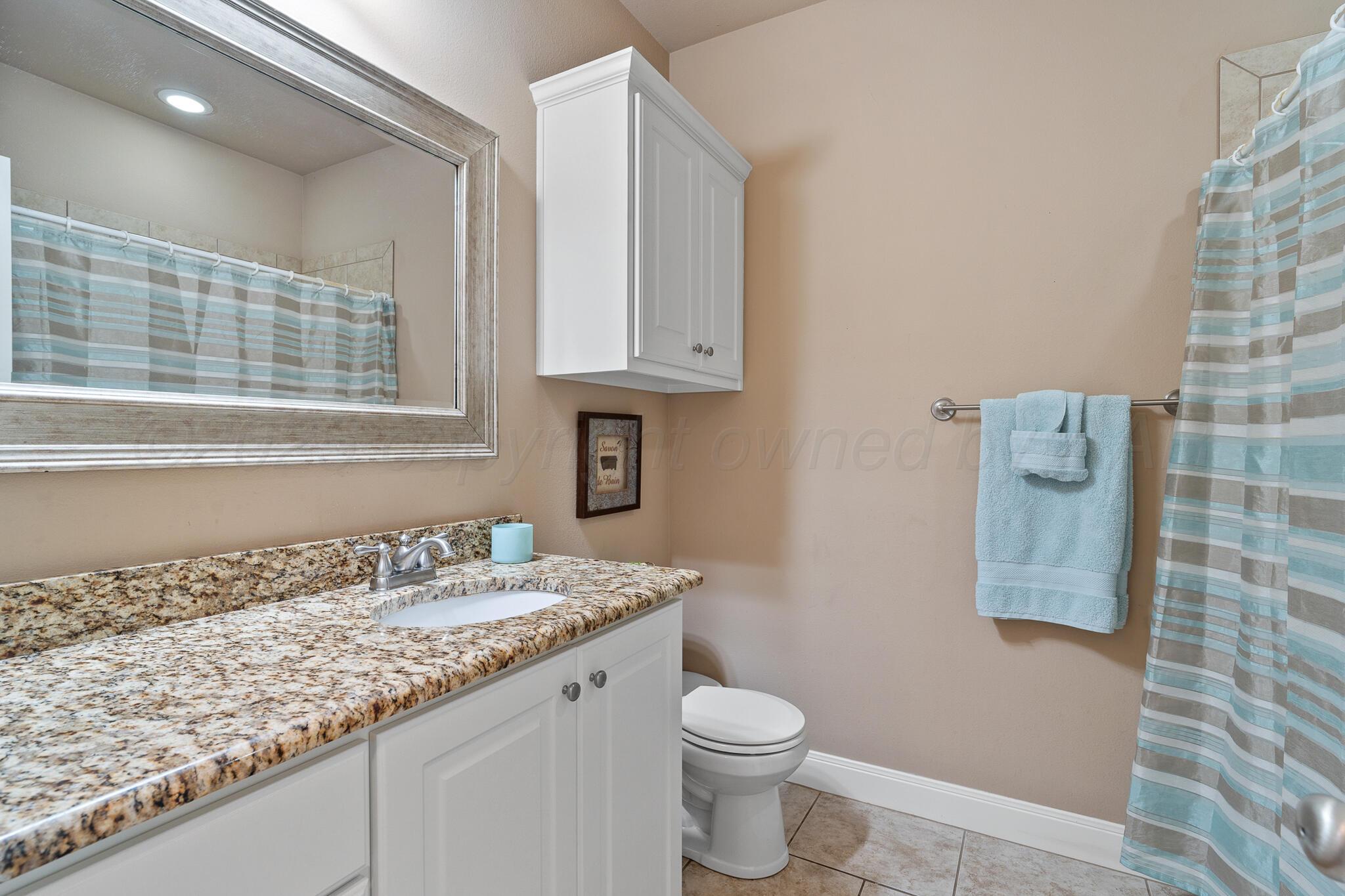 7116 Sinclair Street Amarillo, TX 79119 - Photo 17 of 23 a bathroom with a granite countertop toilet sink and mirror