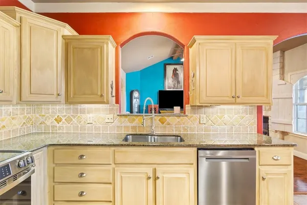 a kitchen with granite countertop a sink stainless steel appliances and cabinets