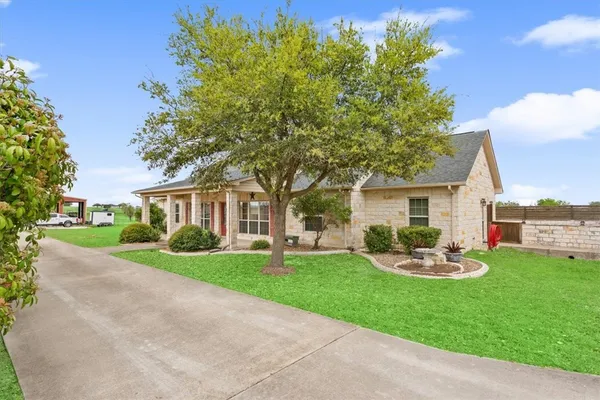 a front view of a house with a garden and trees