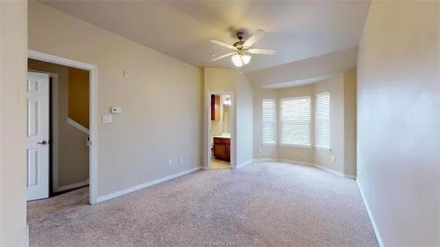 a view of an empty room with chandelier fan