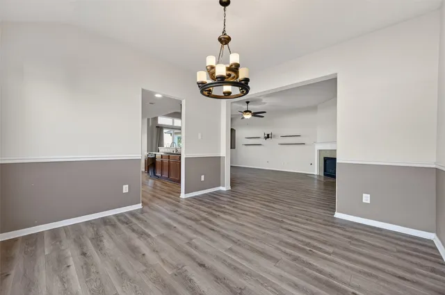 a view of a room with wooden floor ceiling fan and kitchen