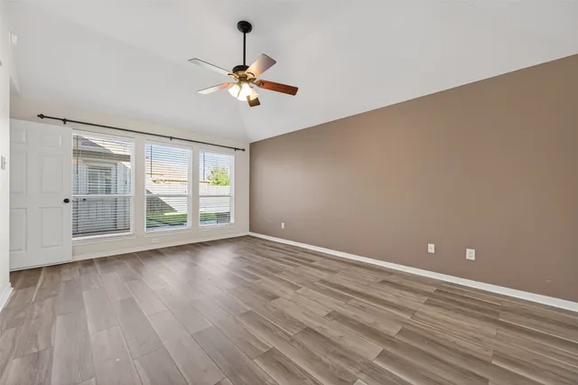 a view of an empty room with a window and wooden floor