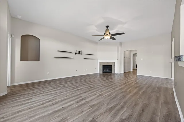 an empty room with wooden floor ceiling fan and windows